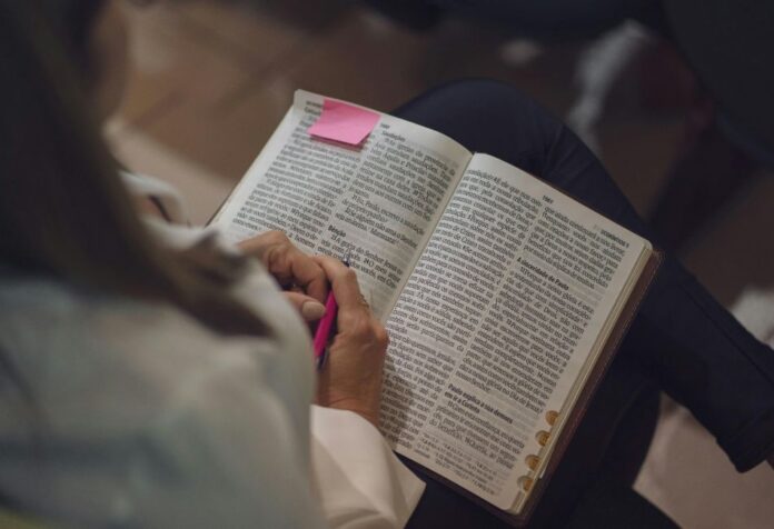 Persona estudiando la Biblia con un marcador y notas, en un ambiente íntimo de reflexión.