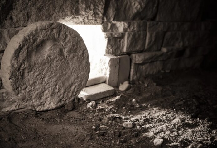 Entrada de una tumba de piedra con la roca movida y luz entrando desde el exterior, simbolizando la resurrección de Jesús.