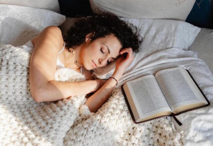 Mujer dormida en una cama junto a una Biblia abierta, en una escena que representa la reflexión cristiana sobre los sueños y el discernimiento espiritual.