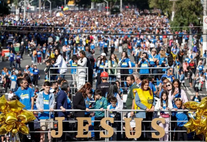 Miles de cristianos evangélicos participan en la Marcha para Jesús en São Paulo, Brasil, avanzando por una amplia avenida mientras cantan, oran y celebran su fe.